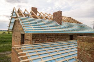 Aerial view of a brick house with wooden roof frame under construction.