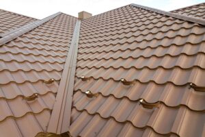 Detail of a house roof surface covered with brown metal tile sheets.