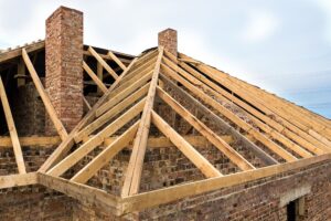 Private residential house with wooden roof frame structure under construction. Unfinished brick building under development.