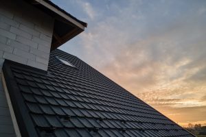 Closeup of house roof top covered with metallic shingles.Tiled covering of building.