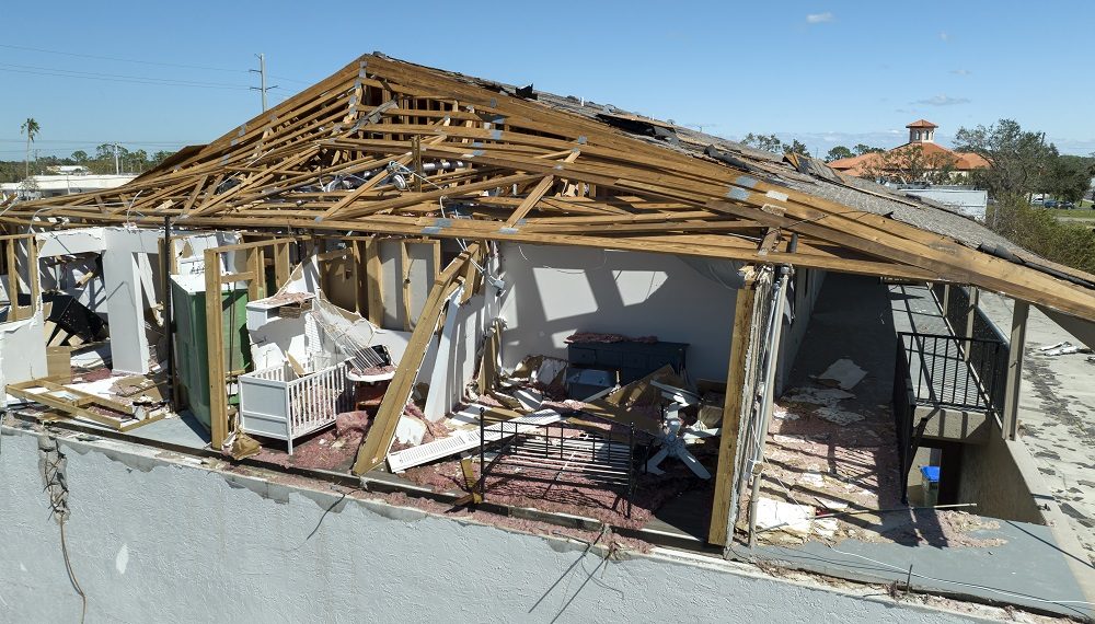 Consequences of natural disaster. Damaged house roof with missing shingles and broken apart walls after hurricane Ian in Florida.