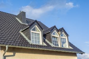 The dormers on the grey slate roof with the sky in the background