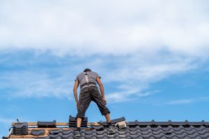 craftsman on the roof of a family house, building a roof covering from ceramic tiles.