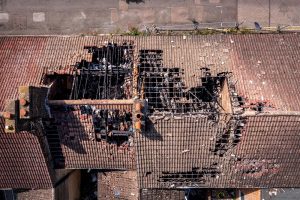 Aerial view directly above a row of burnt out and derelict terraced houses in the North of England with roof damage after a house fire