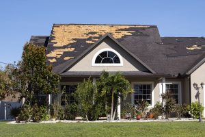 Damaged house roof with missing shingles after hurricane Ian in Florida.