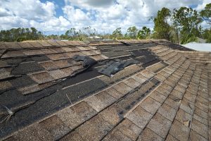 Damaged house roof with missing shingles after hurricane