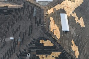 Wind damaged house roof with missing asphalt shingles 