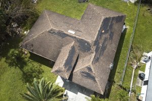 Wind damaged house roof with missing asphalt shingles after a storm