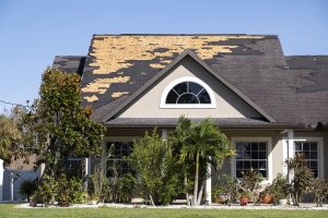 Wind damaged house roof with missing asphalt shingle